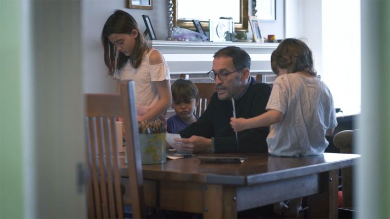 Darin Jensen sits at his wooden dining room table surrounded by his three young kids.
